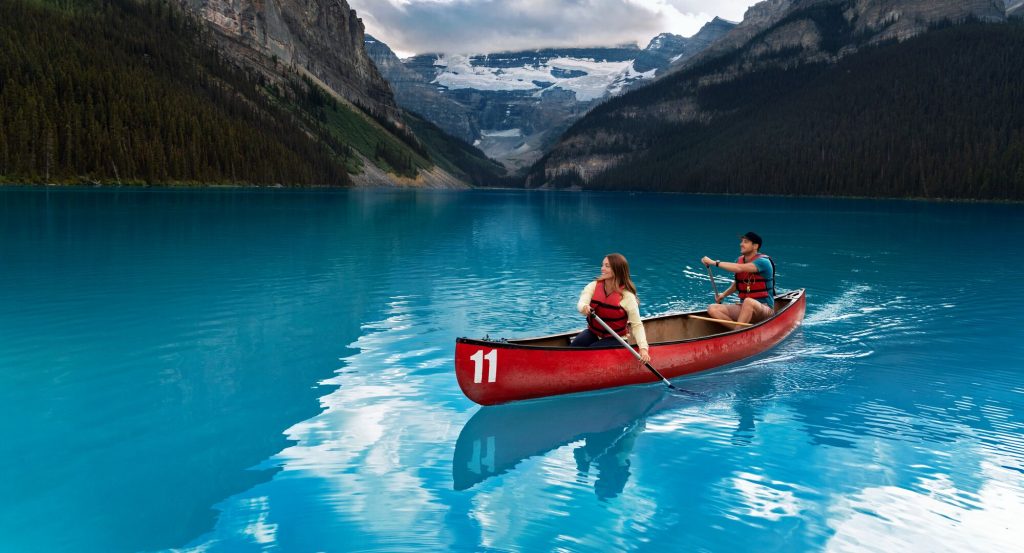 Canoeing on Lake Louise with snow-capped mountains and turquoise glacial waters in Banff Alberta